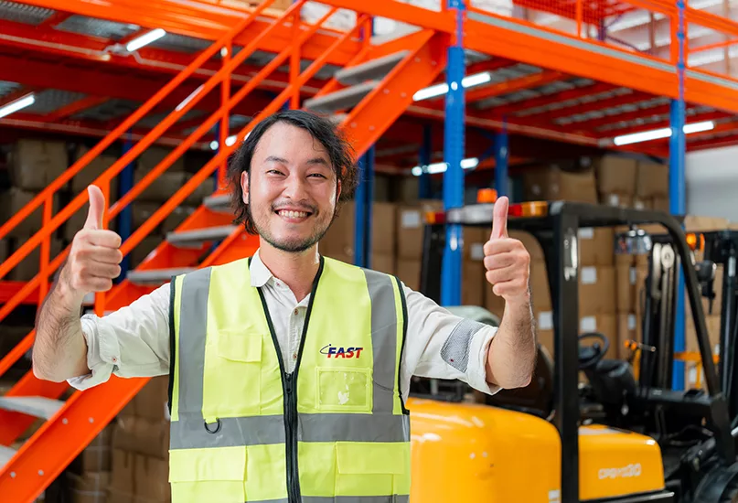 Happy warehouse worker in a safety vest gives a thumbs up